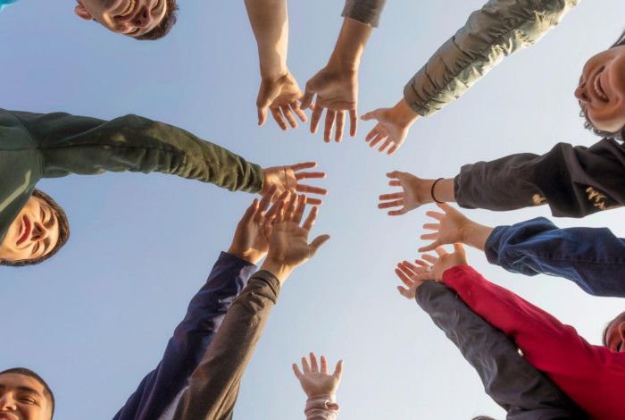 Multicultural group of people, standing in circle and raising their hands to the sky