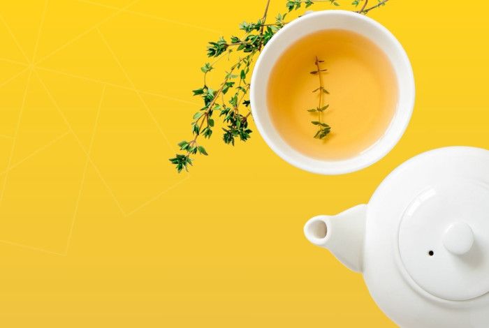 Teapot, herbs and tea in a cup.