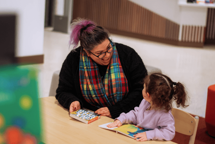 Library staff member with a child reading board books in the library.