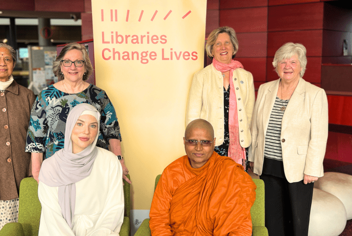 A group of women belonging to different faiths posing together for a photo in the library.
