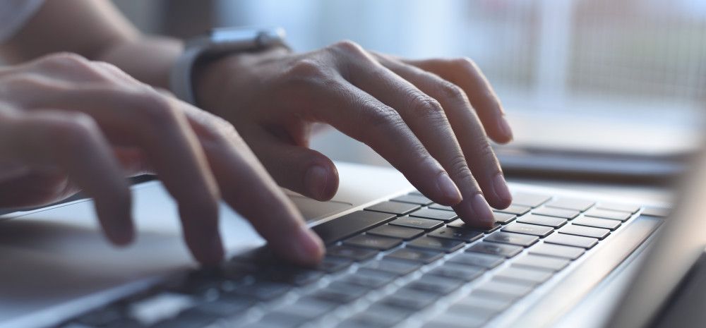 Closeup of a person's hands typing on a laptop.