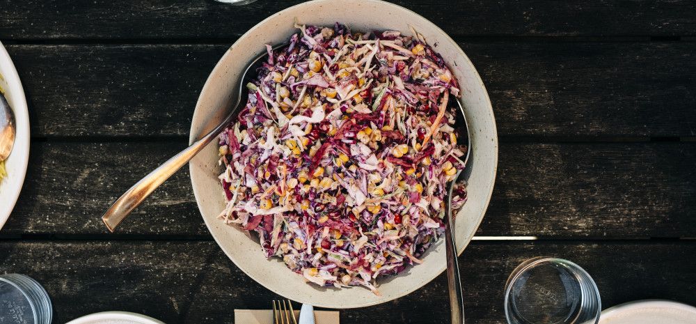 A bowl full of pomegranate salad on a dining table with cutlery.