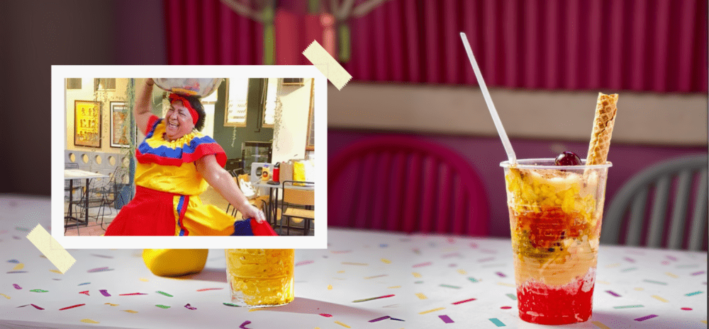 Colombian cup dessert presented on a table with a lady on the side dancing in colombian costume.