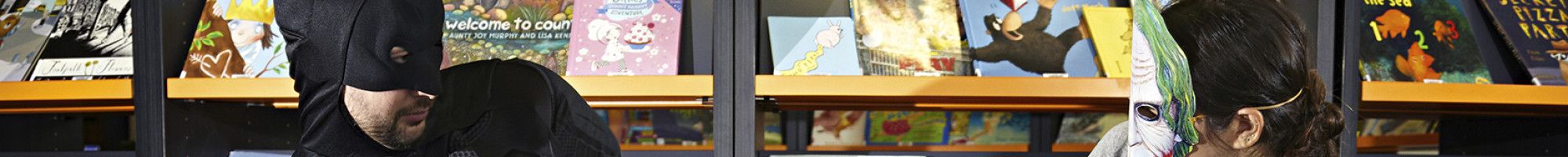 Batman and the Joker cosplay characters fighting over a book