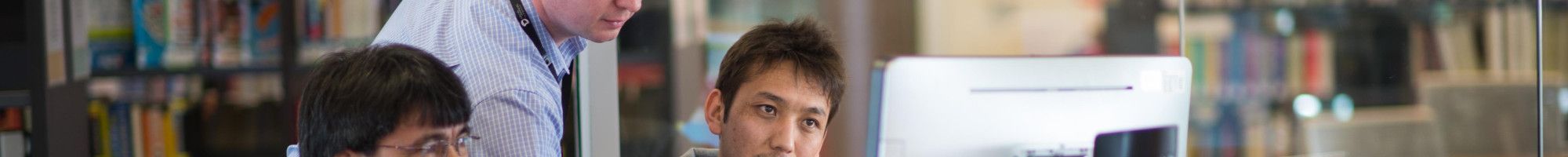 Image: A staff member assisting people to use the computers in the library