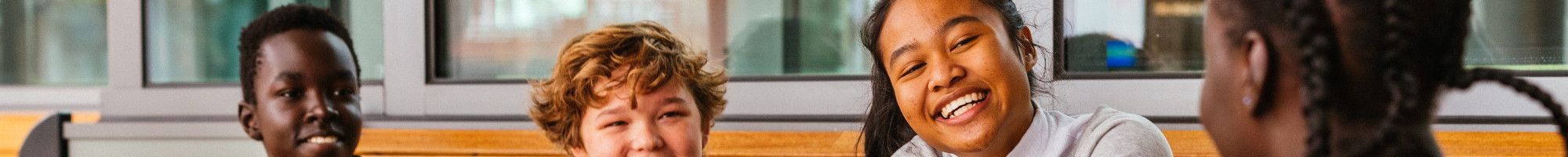 Image: A group of young people at a table smiling