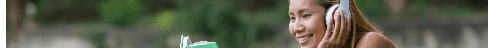 Person wearing headphones lying on the grass looking at a laptop