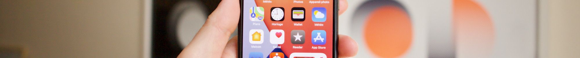 Image: A person holding a mobile phone in their hand with apps visible