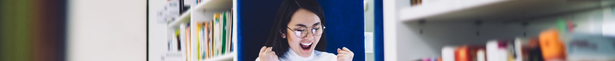 Happy student with laptop in the library.
