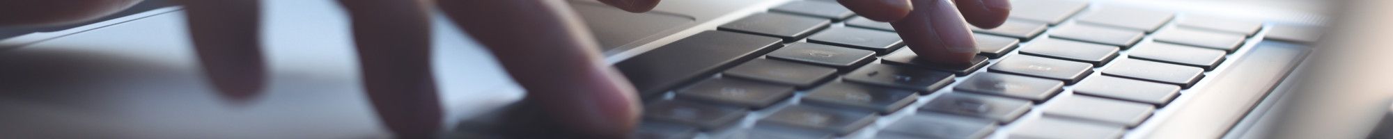 Closeup of a person's hands typing on a laptop.