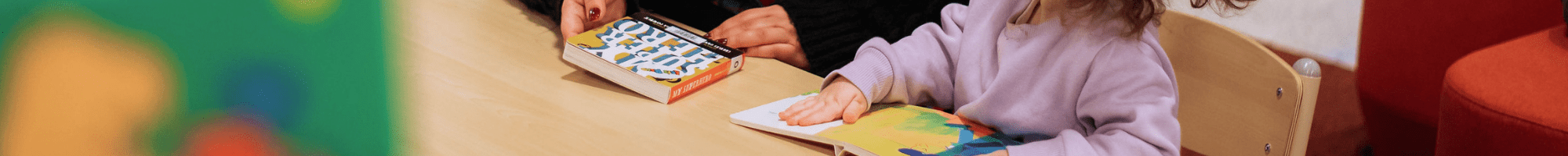 Library staff member with a child reading board books in the library.