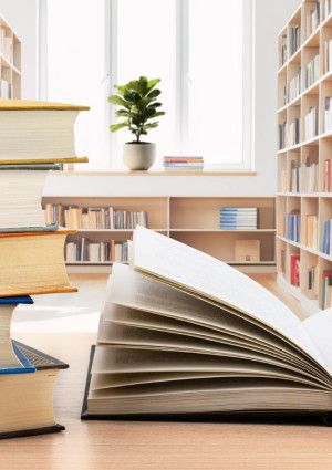Table with an opened book and stack of five books beside it.