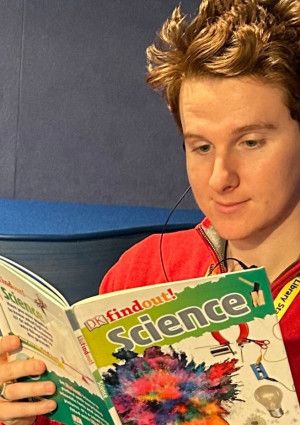 Young library staff member reading a book in the library.