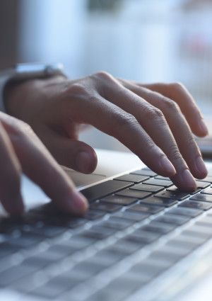 Closeup of a person's hands typing on a laptop.